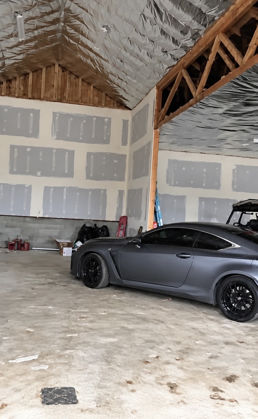Drywall taping in progress inside a large garage